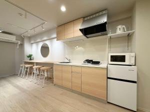 une cuisine avec des appareils électroménagers blancs et des armoires en bois dans l'établissement Clio Matoba by b hotel - Fully Equipped Urban Studio Peaceful Stay, à Ōsukachō