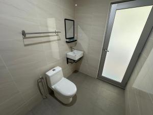 Un baño con inodoro, lavabo y espejo. en Glistar Hotel, en Tampin