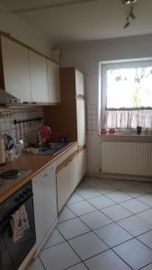Una cocina con gabinetes blancos y una ventana. en Ferienwohnung Hunteblick, en Wildeshausen