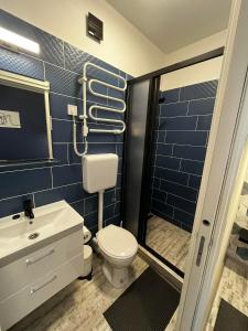 a blue tiled bathroom with a toilet and a sink at Margaréta Studió Apartman in Pusztavacs