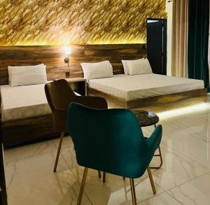 a room with two beds and a chair and a table at Hotel Exclusive in Dargai