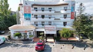 ein weißes Gebäude mit einem davor geparkten Auto in der Unterkunft Ampuria Inn in Empuriabrava