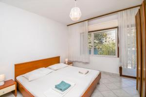 a white bedroom with a bed and a window at Apartments Ivan in Vinišće +37 photos