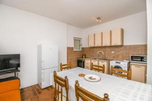 a kitchen with a white table and a white refrigerator at Apartments Ivan in Vinišće