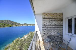 a balcony with a table and chairs and the water at Apartments Ivan in Vinišće