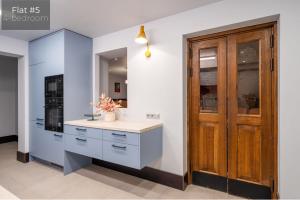 - une cuisine avec des placards bleus et une porte en bois dans l'établissement Dandelion Apartments Lāčplēša, à Riga