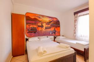 ein Zimmer mit zwei Betten und einem Gemälde an der Wand in der Unterkunft Turunç Pansiyon in Bodrum City + 3 Fotos
