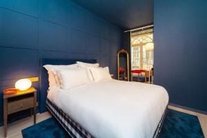 a blue room with a bed and a table and a window at Hotel Kodawari Flores - by Kodawari Residences in Porto