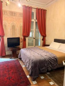 a bedroom with a bed with red curtains and a television at Bartissol et Maillol in Perpignan