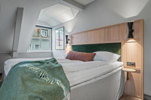 a bedroom with a large bed with a green blanket on it at Quality Hotel Ålesund in Ålesund
