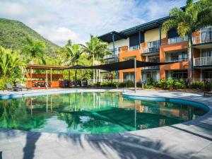 a swimming pool in front of a building at The Sebel Palm Cove in Palm Cove