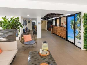 a lobby with a waiting area with a couch and a table at The Sebel Palm Cove in Palm Cove