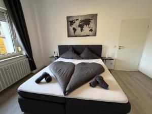 a bed with a heart shaped pillow and shoes on it at Stylish & Relaxing Modernes Apartment mit Privatparkplatz in Gelsenkirchen