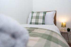 a bed with a green and white pillow and a lamp at Wellington - Telford house - With parking in Wellington