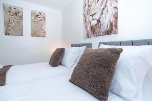 a white bed with white pillows and paintings on the wall at Wellington - Telford house - With parking in Wellington