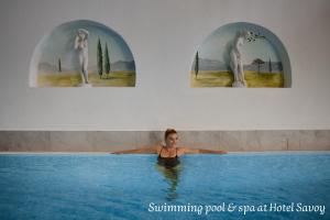 a woman in a swimming pool with four pictures at Ciasa Nives in La Villa