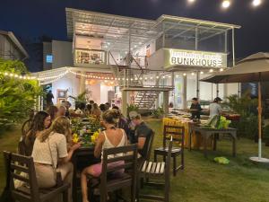 a group of people sitting at tables in front of a building at Bunkhouse Koh Phangan in Thong Sala
