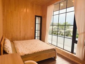 a bedroom with a bed and a large window at Kem Rose Trại Mát in Trai Mat