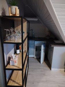 a room with a shelf with glasses and a kitchen at Féerie de la Vigne in Ammerschwihr
