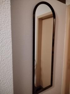 a mirror with a wooden frame on a wall at Féerie de la Vigne in Ammerschwihr