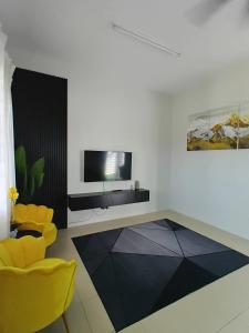 a living room with a television and yellow chairs at D' Tronoh Home in Teronoh