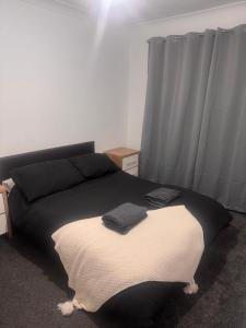 a bedroom with a black and white bed with grey curtains at Nobles Nest in Skegness