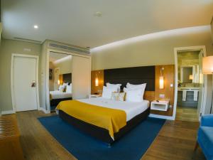 a large bedroom with a large bed with a yellow blanket at Hotel Fonte Velha in Ponte da Barca