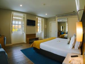 a hotel room with a large bed and a desk at Hotel Fonte Velha in Ponte da Barca