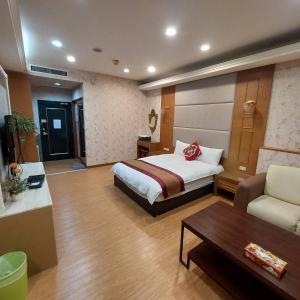 a bedroom with a bed and a couch and a table at Prague Hostel in Kaohsiung