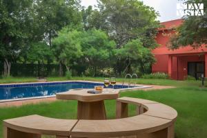 - une table avec deux verres de vin près de la piscine dans l'établissement StayVista at Petals Of Dusk - Outdoor pool, WiFi & BBQ, à Jaipur