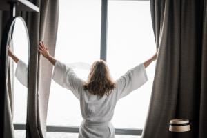 a woman in a white robe looking out of a window at Quality Hotel Ålesund in Ålesund