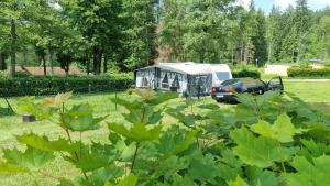 Ein Wohnmobil steht mit einem Auto auf einem Feld in der Unterkunft Klimatisierter exklusiver Caravan mit 240 m umzäunten Stellplatz in Untergriesbach