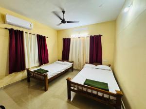 2 Betten in einem Zimmer mit roten Vorhängen in der Unterkunft Texas 3 BHK villa for 13 pax near Airport in Thiruvananthapuram