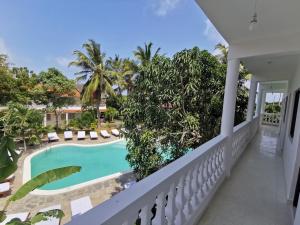a balcony with a swimming pool and palm trees at Thami House in Watamu