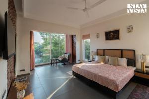 a bedroom with a bed and a large window at StayVista at Villa Aera with Pool, Lawn in Chandīgarh +34 photos