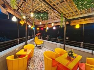 a restaurant with yellow chairs and tables on a balcony at Tathastu Stay in Dehradun