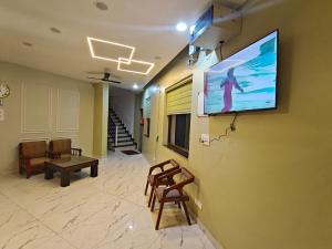 a room with a tv on a wall with chairs at Tathastu Stay in Dehradun