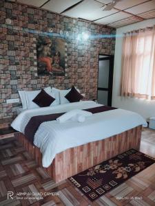 a bedroom with a large bed with a brick wall at Alampat Nest in Alwar