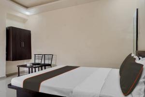 a bedroom with a bed and a table and a chair at Hotel O Parinda Lodging in Chinchwad