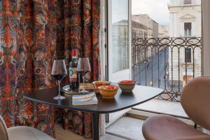 a table with two glasses of wine on a balcony at Belduomo Catania Rooms & Flat in Catania