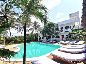 a resort pool with lounge chairs and palm trees at Thami House in Watamu