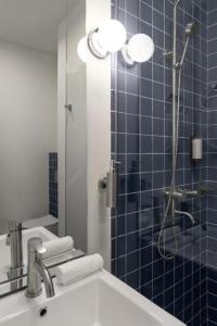 a blue tiled bathroom with a shower and a sink at Stars by Castor & Pollux in Tbilisi City