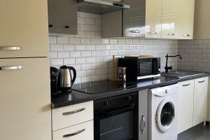 a kitchen with a microwave and a washer and dryer at LE COSY Basel Euroairport ! Parking Privé in Saint-Louis +13 photos