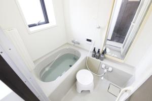 a white bathroom with a tub and a toilet at Corp F Haneda in Tokyo