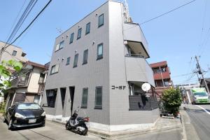 a white building with a scooter parked in front of it at Corp F Haneda in Tokyo