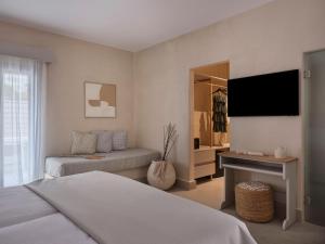 a bedroom with a bed and a flat screen tv at Salt Suites Paros in Naousa