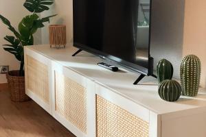 a flat screen tv sitting on top of a white dresser at LE COSY Basel Euroairport ! Parking Privé in Saint-Louis