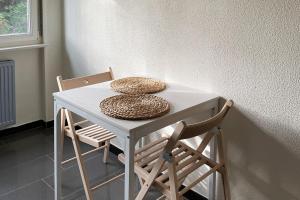 a table with two chairs and a table with two hats on it at LE COSY Basel Euroairport ! Parking Privé in Saint-Louis