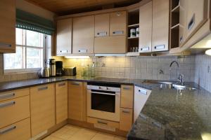 a kitchen with wooden cabinets and granite counter tops at Log Chalet Tallero in Luosto