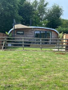 une petite cabane dans un champ avec une clôture dans l'établissement Willowbrook Luxury Log Cabin with private hot tub, à Kings Norton